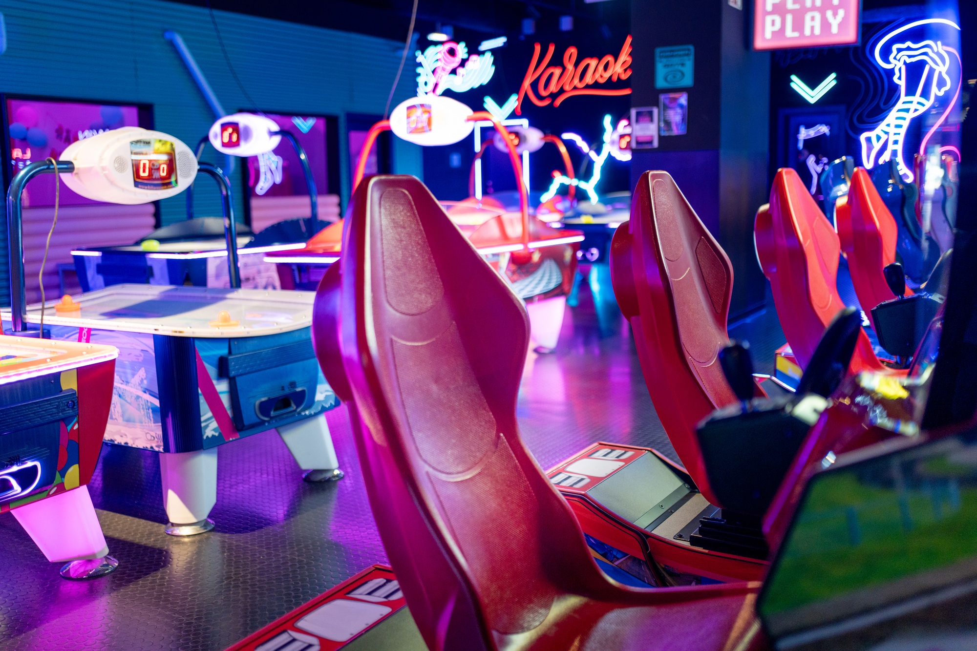 Row of racing arcade machines inside neon lit shopping mall